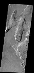 In this part of the Tharsis region on Mars, old lava flows have been fractured. Younger lava flows are unfractured (flow at bottom) as seen by NASA's Mars Odyssey spacecraft.