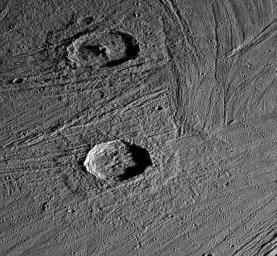 This image captured by NASA's Galileo spacecraft shows an oblique view of two fresh impact craters in bright grooved terrain near the north pole of Jupiter's moon, Ganymede.