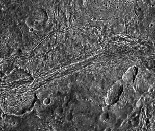 This image captured by NASA's Galileo spacecraft shows dark terrain of Nicholson Regio on Jupiter's moon, Ganymede. On the left is a crater that has been torn apart by tectonic forces.