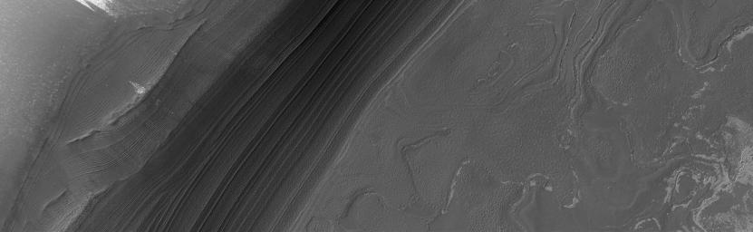 NASA's Mars Global Surveyor shows a nearly ice-free view of layers exposed by erosion in the north polar region. The light-toned patches are remnants of water ice frost.