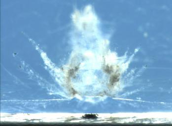 This image from NASA shows a particle impact on the aluminum frame that holds the aerogel tiles. The debris from the impact shot into the adjacent aerogel tile producing the explosion pattern of ejecta framents captured in the material.