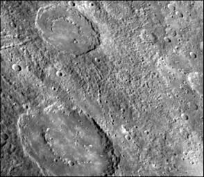 The craters in this image NASA's Mariner 10 spacecraft, which launched in 1974, have interior rings of mountains and ejecta deposits which are scarred by deep secondary crater chain groves. 
