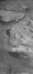NASA's Mars Global Surveyor shows eroded bedrock among the mountains of western Argyre. Smooth on Mars, dark areas are patches of windblown sand.