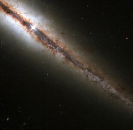 An amazing 'edge-on' view of a spiral galaxy 55 million light years from Earth has been captured by the Hubble Space Telescope. The image reveals in great detail huge clouds of dust and gas extending along and above the galaxy's main disk. 