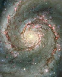 The image from NASA's Hubble Telescope shows spiral arms and dust clouds in the nearby Whirlpool galaxy. Visible starlight and light from the emission of glowing hydrogen is seen, which is associated with the most luminous young stars in the spiral arms.