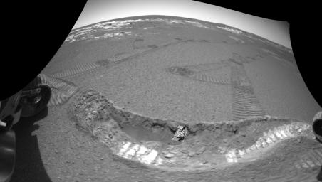 NASA's Mars Exploration Rover Opportunity shows the crater floor at Meridiani Planum, Mars, after the rover dug a trench on Feb. 16, 2004. A small patch of soil is seen in the center of the trench wall with the rovers' tracks leading off in the distance.