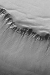 NASA's Mars Global Surveyor shows gullies and slopes in the walls of a deep pit in the south polar region of Mars.