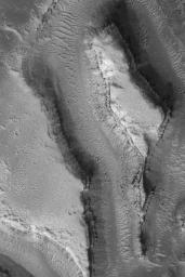 NASA's Mars Global Surveyor shows landforms in the Granicus Valles region, west of the Elysium volcanoes on Mars. Layered rock and some large, dark boulders are among the features observed.