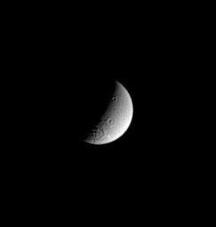 Saturn's cratered moon Dione displays a large impact basin near its south pole in this image captured by NASA's Cassini spacecraft on Nov. 2, 2004.