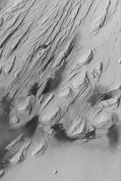 NASA's Mars Global Surveyor shows the effects of severe wind erosion of layered sedimentary rock in the Aeolis region of Mars. The sharp ridges formed by wind movement are known as yardangs.