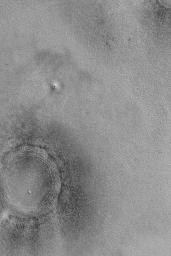 NASA's Mars Global Surveyor shows the location of a somewhat filled and buried meteor impact crater on the northern plains of Mars. The dark dots are boulders.