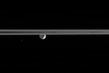 Gazing across the ringplane, NASA's Cassini spacecraft spots a Saturn-lit Mimas and the tiny Trojan moon Helene. Only the bright crescent on Mimas' eastern limb is lit by the Sun; the moon's night side is illuminated by Saturnshine.