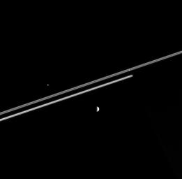 NASA's Cassini spacecraft captures three moons at once as they hurtle around Saturn. In the background, Saturn's night side covers the more distant portion of the rings, betraying the presence of the unseen giant.