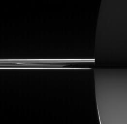 NASA's Cassini spacecraft looked toward the night side of Saturn to spy the darkened orb of Mimas barely visible here near the center of the image hugging the planet's shadow.