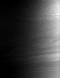 Saturn's clouds billow and swirl in the turbulent zones of shear between eastward- and westward-flowing jets. This view from NASA's Cassini spacecraft looks toward the terminator on Saturn, where night gives way to day.