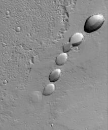 NASA's Mars Global Surveyor shows a chain of collapse pits on a dust-mantled, lava-covered plain northeast of Ascraeus Mons -- one of the giant volcanoes located in the Tharsis region of Mars.