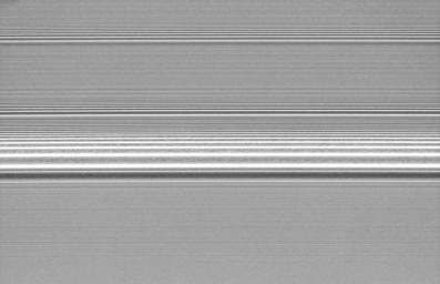 Several spiral density waves in Saturn's A ring are seen in this detailed view from NASA's Cassini spacecraft. There is a grainy texture visible between the brightness peaks in the most prominent wave.