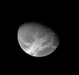 NASA's Cassini spacecraft looks down from high latitude over Dione and the system of wispy fractures that coats the moon's trailing side.