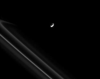 Saturn's moon Prometheus pulls away from an encounter with the narrow F ring, trailing a streamer of fine, icy particles behind it in this image captured by NASA's Cassini spacecraft on May 25, 2008.