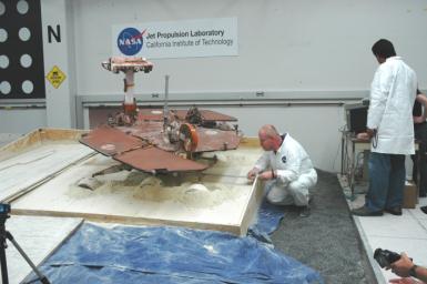 After commanding five of a test rover's six wheels to drive forward, rover driver Paolo Bellutta (left) measures how much the rover moved sideways, downslope, during the maneuver.