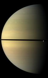 Saturn, stately and resplendent in this natural color view taken by NASA's Cassini spacecraft, dwarfs the icy moon Rhea. Rhea orbits beyond the rings on the right of the image. Tethys shadow is visible on the planet on the left of the image.