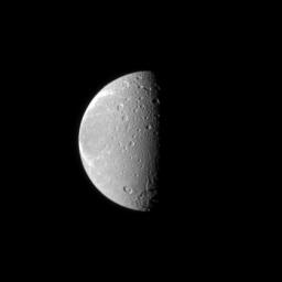 The tortured terrain of Saturn's moon Dione is documented in this NASA Cassini spacecraft image. The wispy fractures on the moon's trailing hemisphere can be seen on the left, and cratered terrain on the moon's anti-Saturn side dominates the center.