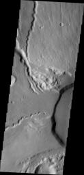 This NASA 2001 Mars Odyssey spacecraft image shows the western edge of the summit caldera of Ceranus Tholus, one of the smaller volcanic constructs of the Tharsis region. Several channels dissect the western flank of the volcano.