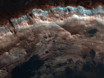 NASA's Mars Reconnaissance Orbiter shows the surface outside this large crater is relatively dark, while the interior wall of the crater exposes lighter, layered bedrock of diverse colors.