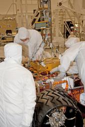 In this photograph, technicians and engineers inside a clean room at NASA's Jet Propulsion Laboratory, Pasadena, Calif., position NASA's Sample Analysis at Mars (SAM) above the mission's Mars rover, Curiosity, for installing the instrument.