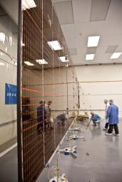 Technicians test the deployment of one of the three massive solar arrays that power NASA's Juno spacecraft.