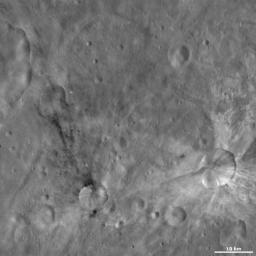 This image from NASA's Dawn spacecraft of asteroid Vesta shows Sossia and Canuleia craters. Sossia is surrounded by dark material in the bottom left of the image and Canuleia is the larger crater surrounded by bright material at bottom right.