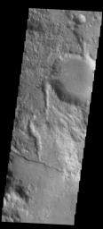 This image captured by NASA's 2001 Mars Odyssey spacecraft shows a channel entering a crater in the region called Libya Montes.