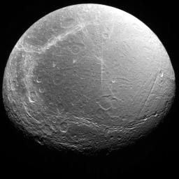 Cracks, canyons, craters, and streaks are seen in this image of Saturn's icy moon, Dione, taken from Voyager 2 on August 3, 2005.