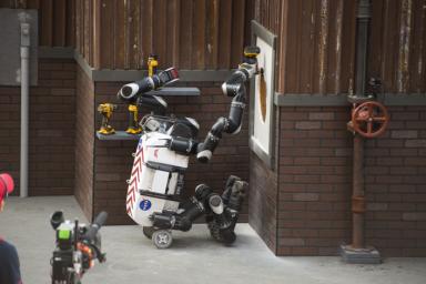 Using a cordless power drill, RoboSimian cuts a hole into a panel of drywall to complete one of the tasks in the DARPA Robotics Challenge Finals.