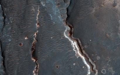 This observation from NASA's Mars Reconnaissance Orbiter shows an interesting crater floor with what appear to be inverted channels, rounded lobe-like landforms, and light-toned layered deposits along the southern portion of the crater wall.