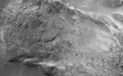 The striking feature in this image from NASA's Mars Reconnaissance Orbiter is a boulder-covered landslide along a canyon wall. Landslides occur when steep slopes fail, sending a mass of soil and rock to flow downhill, leaving a scarp atop the slope.