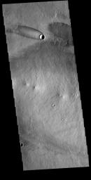 The 'tail' behind the crater at the top of this image from NASA's 2001 Mars Odyssey spacecraft is called a windstreak. This feature is formed by winds blowing over/in and around the crater.