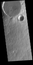 This image captured by NASA's 2001 Mars Odyssey spacecraft shows two circular features. The flat floored feature is the summit caldera of Elysium Mons and the bowl-shaped feature next to the caldera is an impact crater.