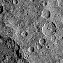 In this densely cratered area of Ceres, NASA's Dawn spacecraft spotted Tupo Crater, with its complex, hummocky interior, at center right. A portion of the rim of Darzamat Crater appears with dark shadows at lower left.