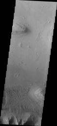 Coprates Chasma is one of the numerous canyons that make up Valles Marineris. This image from NASA's 2001 Mars Odyssey spacecraft shows a relatively smooth floor, with a group of sand dune forms located against the wall of the chasma (bottom of image).