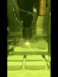 This video clip shows a 3D printing technique where a printer head scans over each layer of a part, blowing metal powder which is melted by a laser.