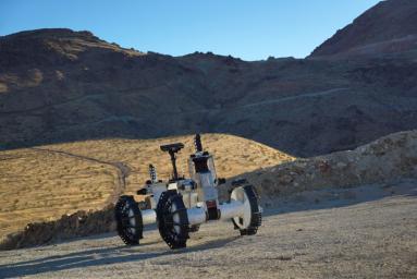The DuAxel rover is seen here participating in field tests in the Mojave Desert. The four-wheeled rover is composed of two Axel robots. One part anchors itself in place while the other uses a tether to explore otherwise inaccessible terrain.