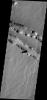 The two depression crossing this image are called Pavonis Fossae and are located just north of the volcano in this image captured by NASA's 2001 Mars Odyssey spacecraft.