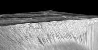 Dark narrow streaks, called 'recurring slope lineae,' emanate from the walls of Garni Crater on Mars, in this view constructed from observations by the HiRISE camera on NASA's Mars Reconnaissance Orbiter.