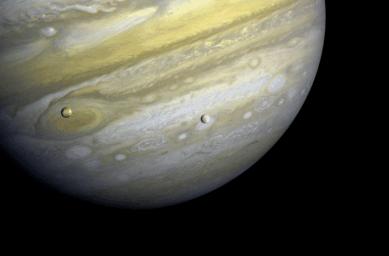NASA's Voyager 1 took this photo of Jupiter and two of its satellites (Io, left, and Europa) on Feb. 13, 1979. Io is above Jupiter's Great Red Spot; Europa is above Jupiter's clouds. The poles are dark and reddish.
