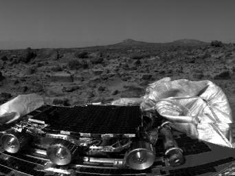 NASA's undeployed Sojourner rover is seen still latched to a lander petal in this image, taken on July 4, 1997, the lander's first day on Mars. Portions of a petal and deflated airbag are in the foreground.