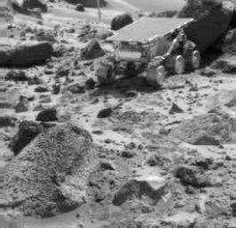 NASA's Sojourner rover is seen next to the rock 'Shark,' in this image taken by the Imager for Mars Pathfinder (IMP) near the end of daytime operations on Sol 52. The rover's APXS is deployed against the rock. The rock 'Wedge' is in the foreground.