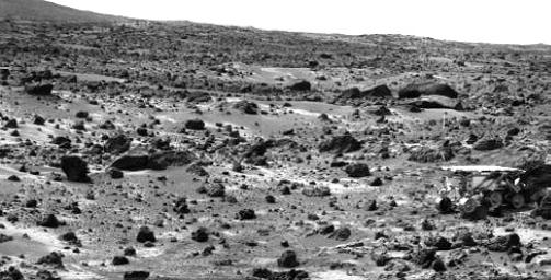 This image taken on the morning of Sol 80 (September 23, 1997) shows NASA's Sojourner rover with its Alpha Proton X-ray Spectrometer (APXS) deployed against the rock 'Chimp.' On the left horizon is the rim of 'Big Crater,' 2.2 km away.
