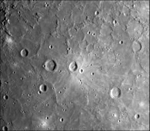 A dark, smooth, relatively uncratered area on Mercury was photographed two hours after NASA's Mariner 10 flew by the planet. The prominent, sharp crater with a central peak is 30 kilometers (19 miles) across.