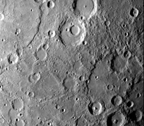 NASA's Mariner 10 photo reveals a heavily cratered terrain on Mercury with a prominent scrap extending several hundred kilometers across the upper left. A crater, nested in a larger crater, is at top center. 